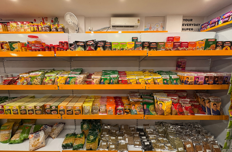 Organized grocery shelves inside a SuperKirana supermarket with neatly arranged packaged food products